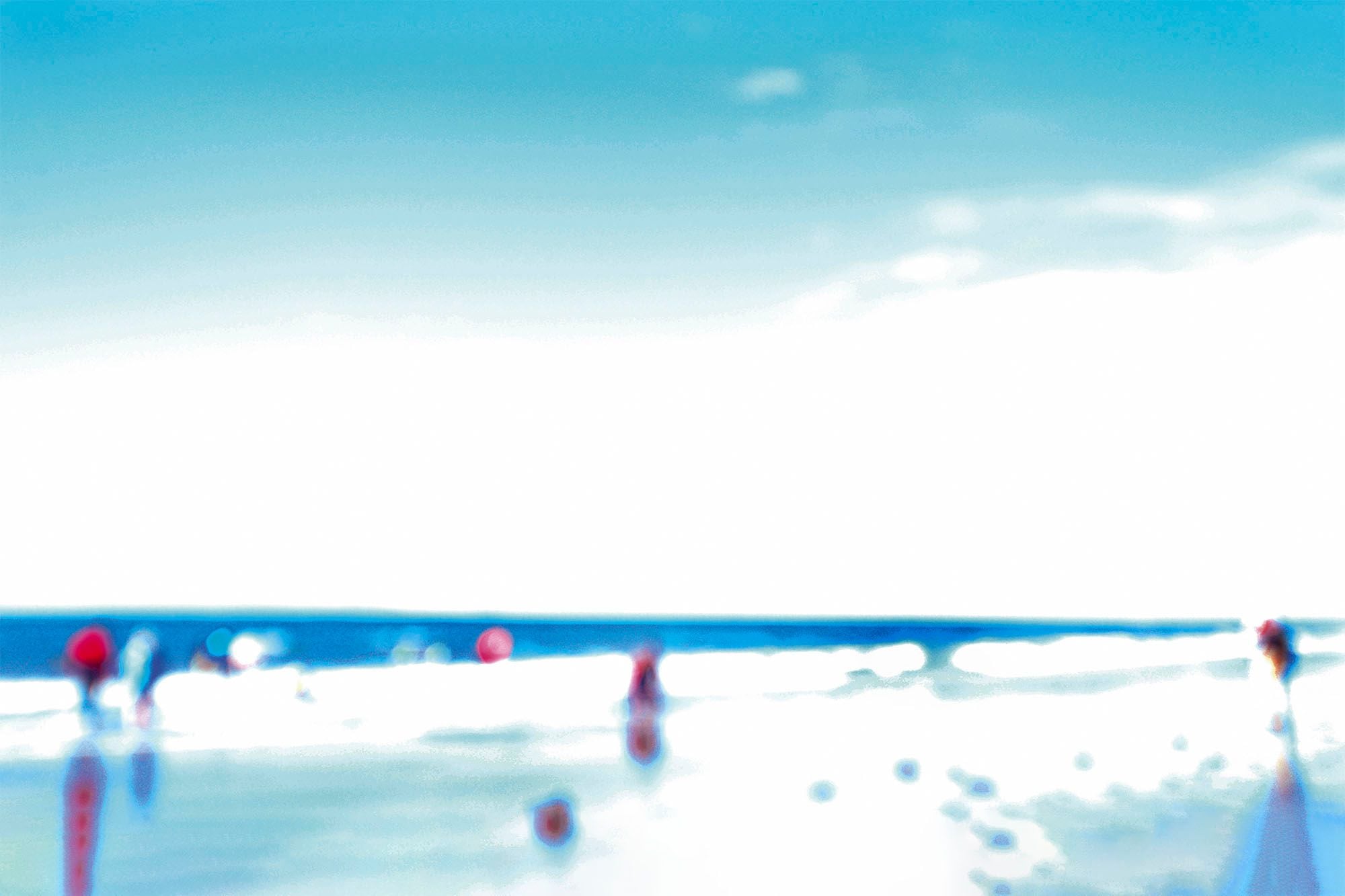 Bright, washed-out beach scene with small figures in red paddling at the water's edge under a blue sky